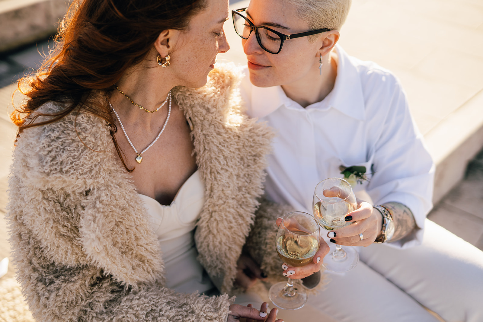 two brides drink a glass of white wine in Lisbon on their elopement day in the winter sun