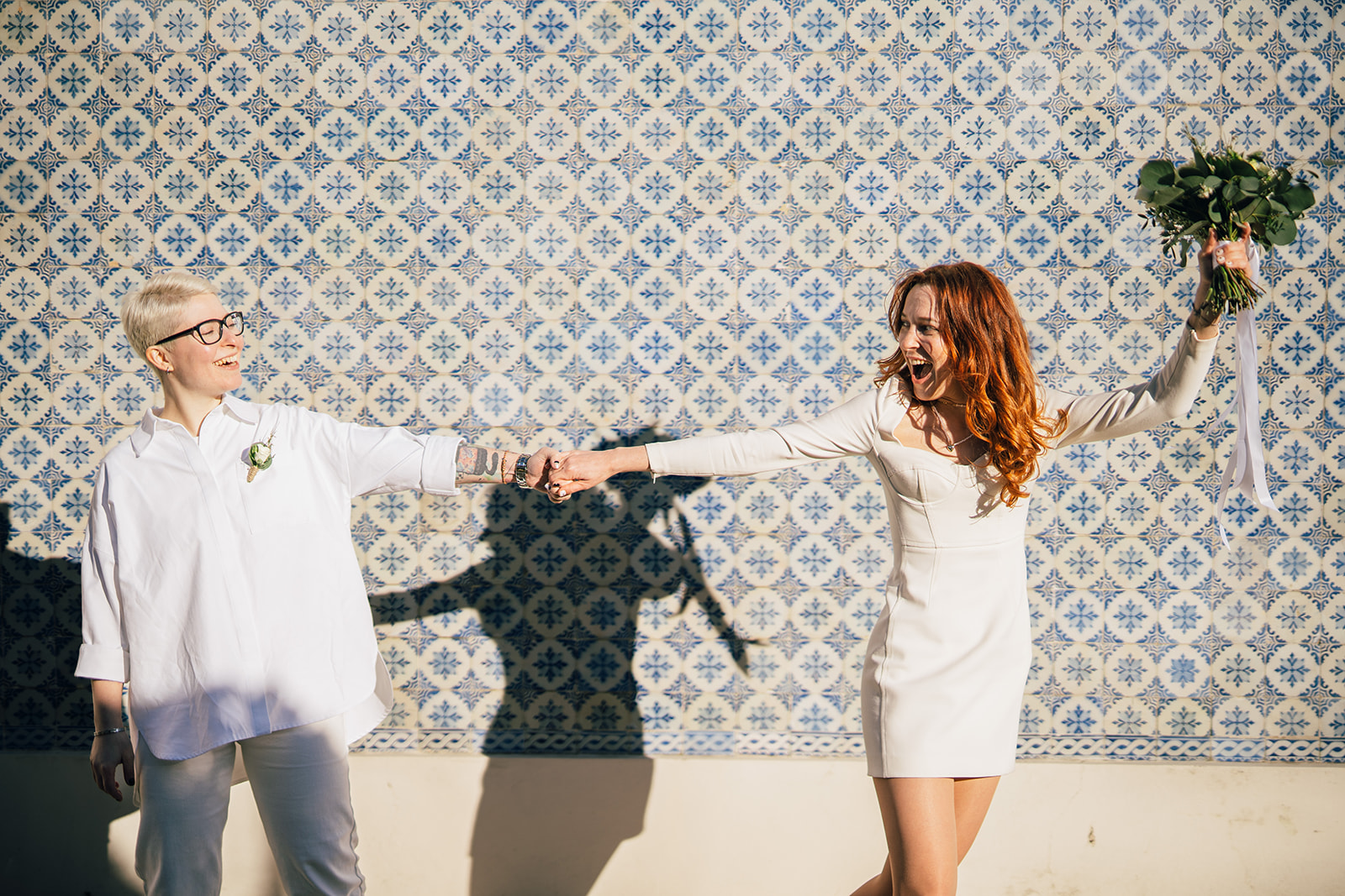 two brides walk in Lisbon on their elopement day against painted ceramic tiles