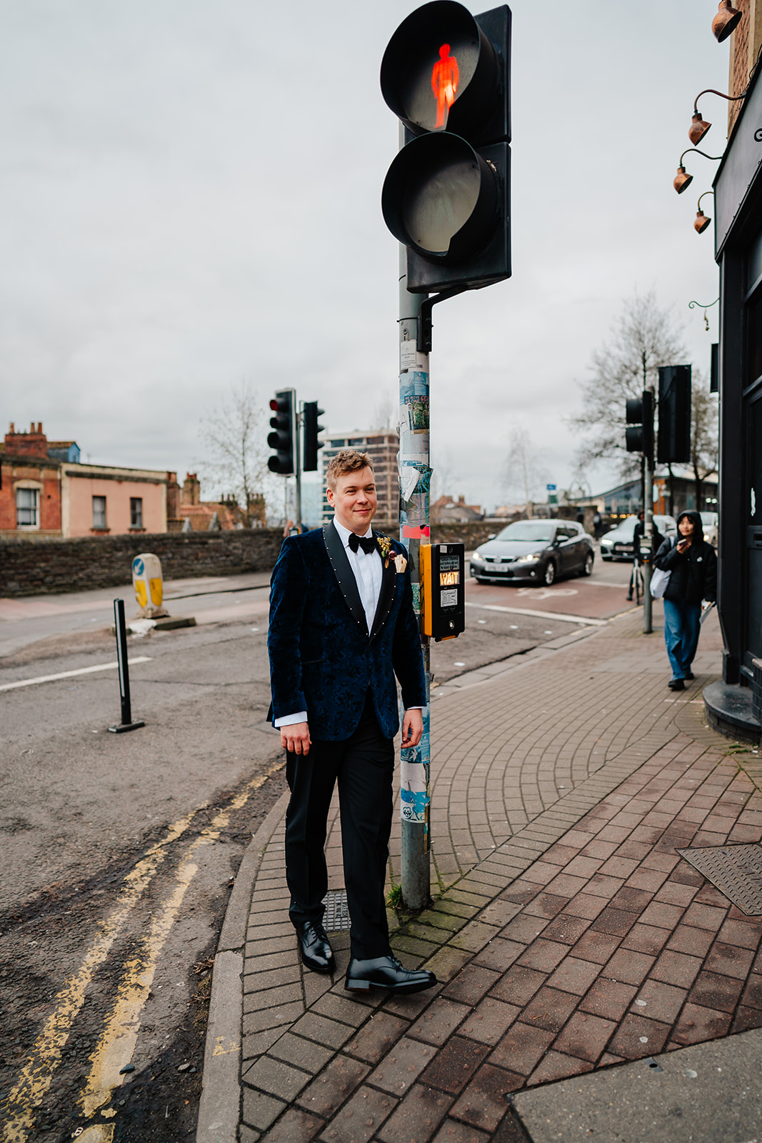 Groom leaning against traffic light on blue suit