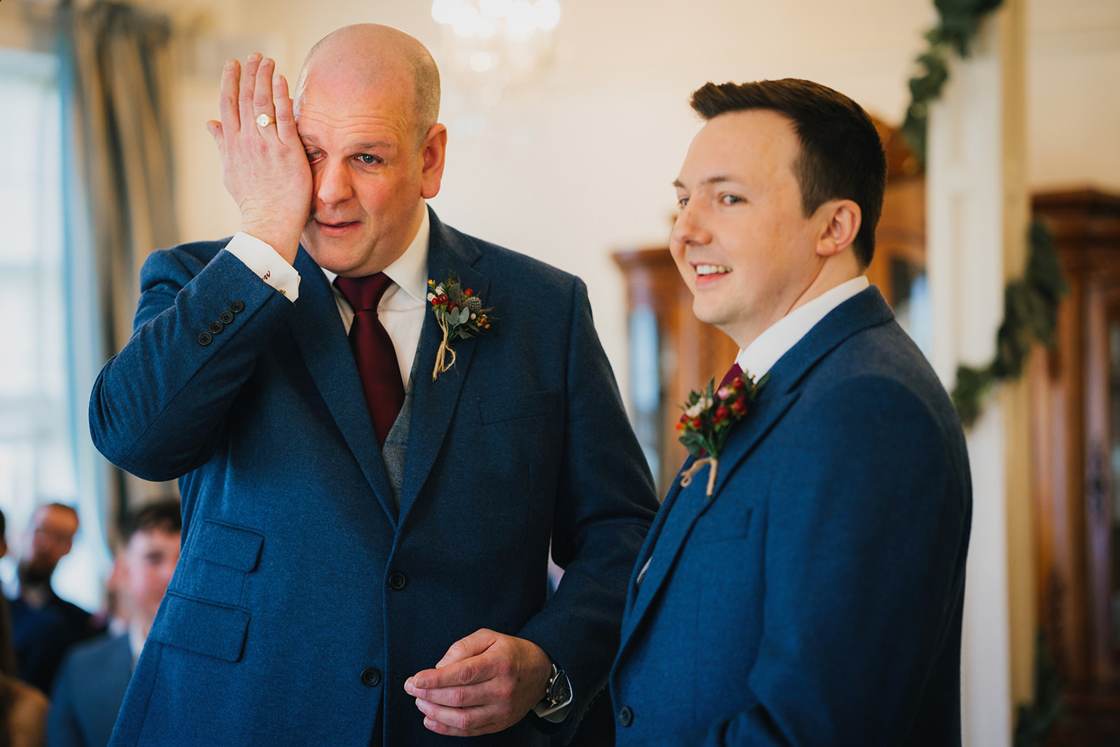 one of the grooms wipes away his tears whilst the other smiles