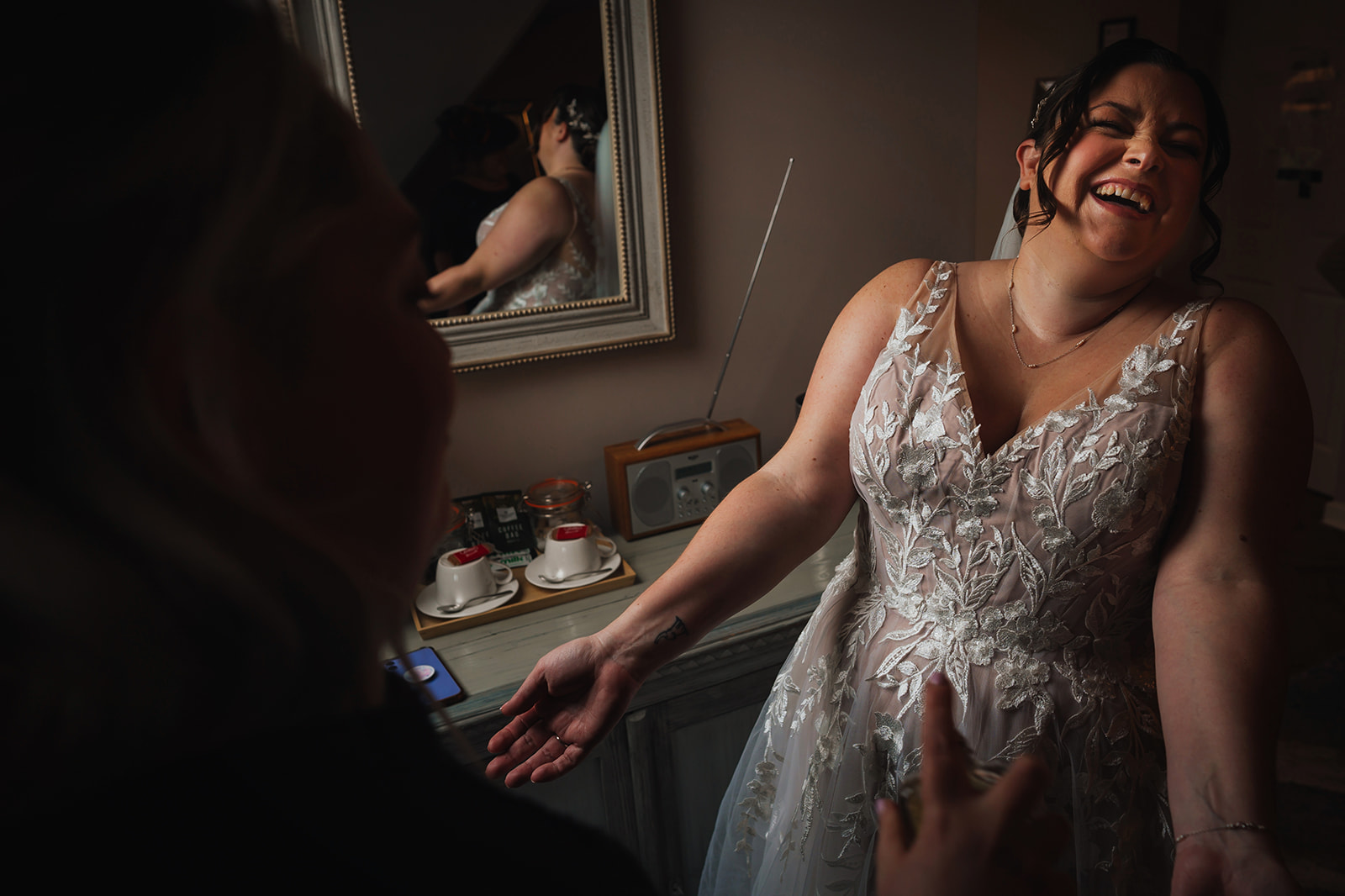 The bride laughs as her make-up artist sprays perfume on her wrists