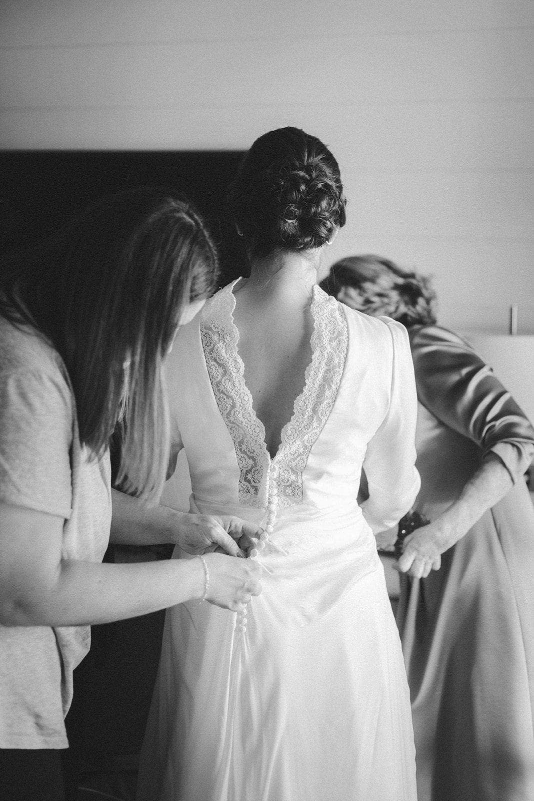 Familiares de la novia la ayudan a ponerse el vestido 