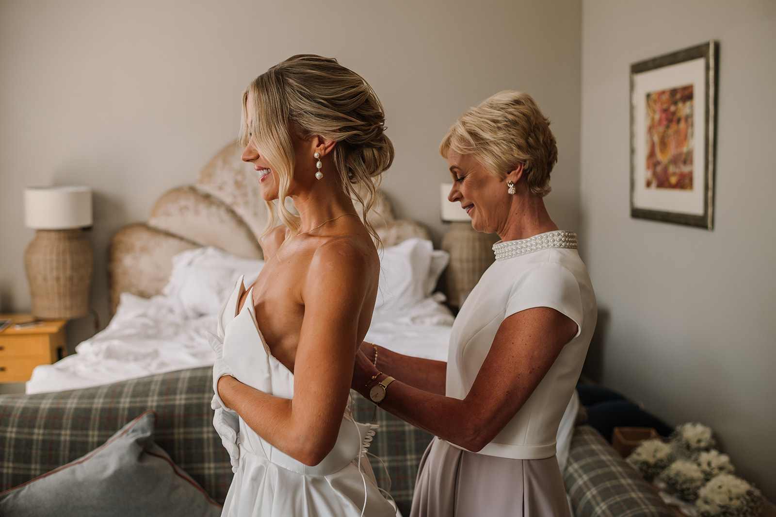 Photography of Bride's mother helping daughter into dress from Anna Bridal