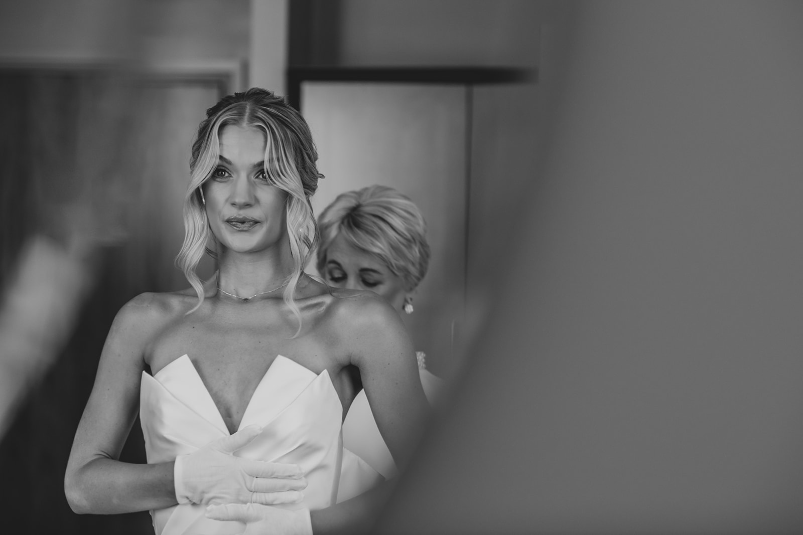 Candid photo of Bride's mother helping daughter into wedding dress