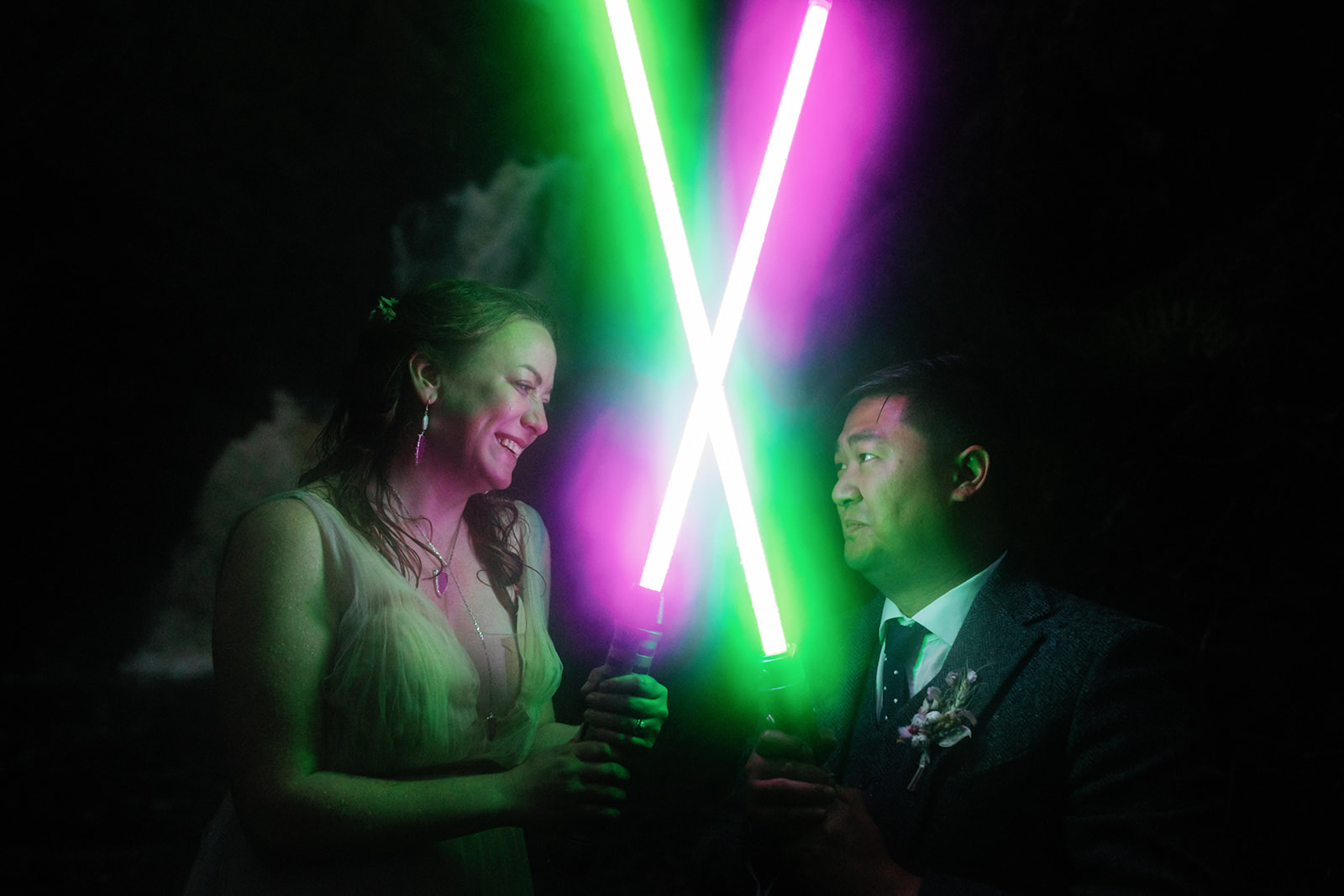 Bride and groom holding lightsabers and looking at each other in the dark during an isle of skye elopement