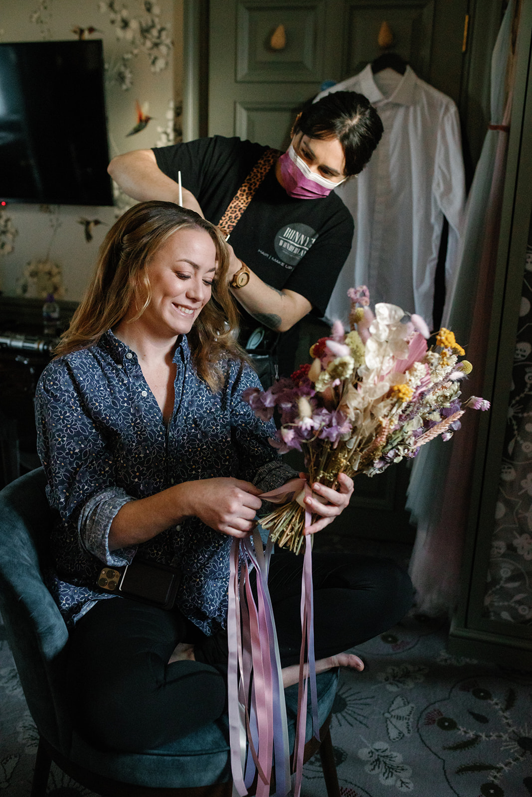 Bride looking at colourful dried flowers whilst having hair done by Bonnys Wonderland