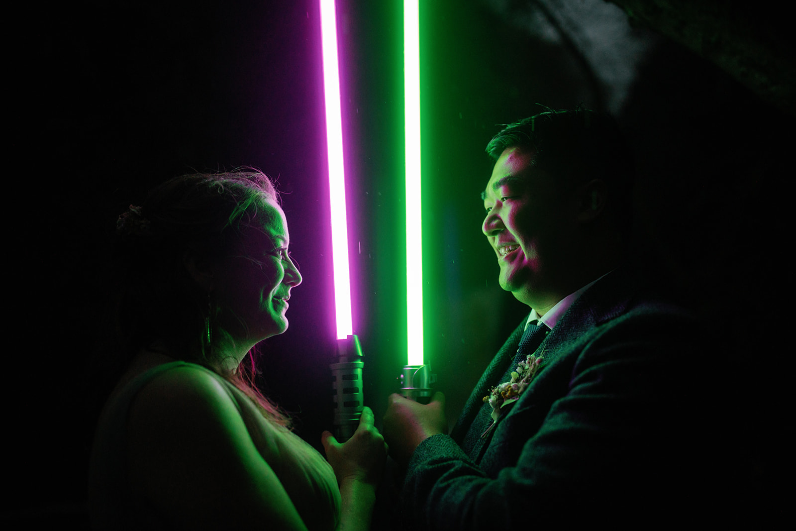 Mellie and Andrew pose for their evening Isle of Skye elopement photos while holding Star Wars light sabers as props.