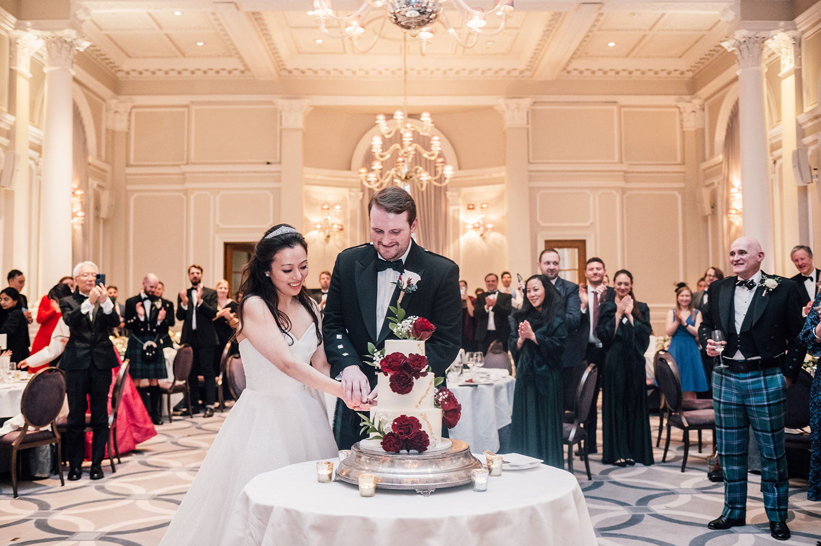 Bride and Groom cutting the cake in the ballroom at Corinthia hotel in London