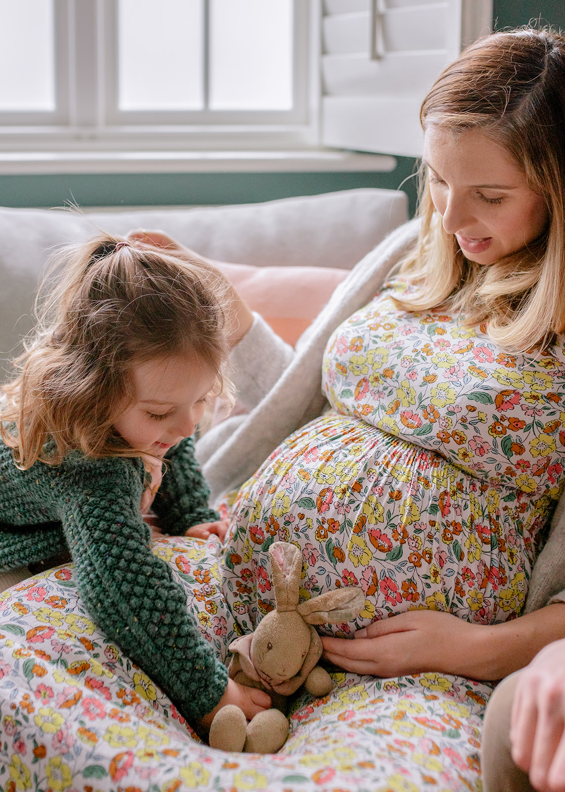 a little girl pointing her toy at her mum pregnant tummy during the natural maternity photography by agi lebiedz