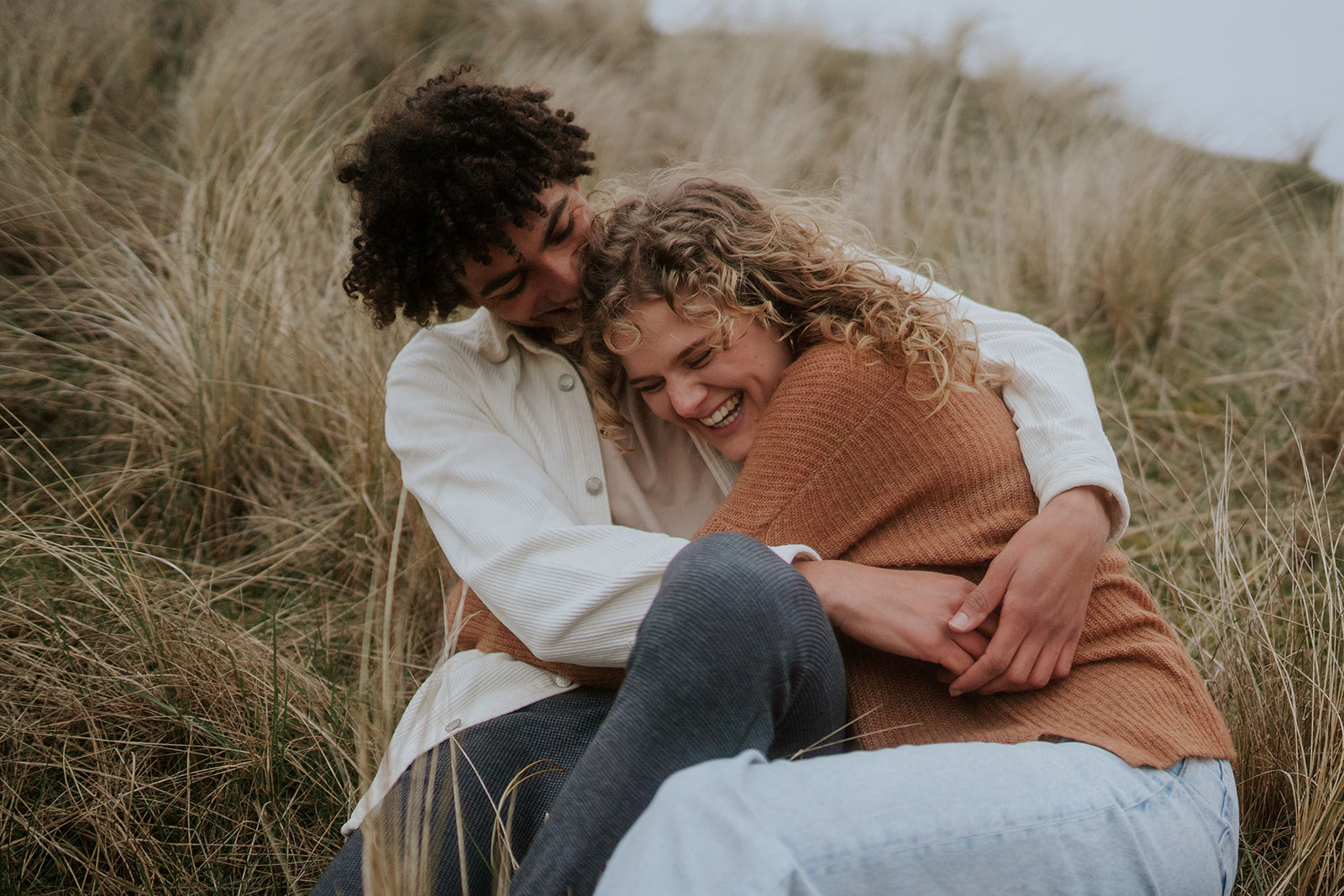 Couple cuddling in long Segge gras in the dunes of Netherlands.