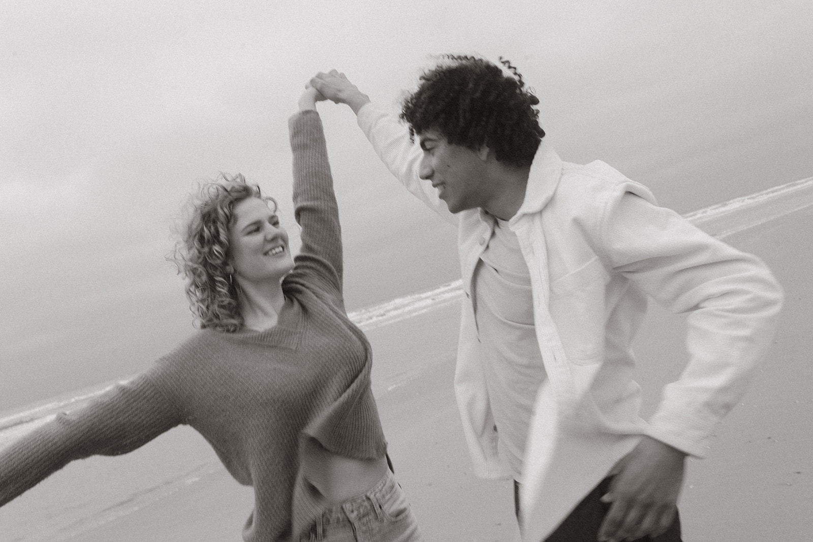 Couple dancing on the shoreline of netherlands. The picture is black and white. 