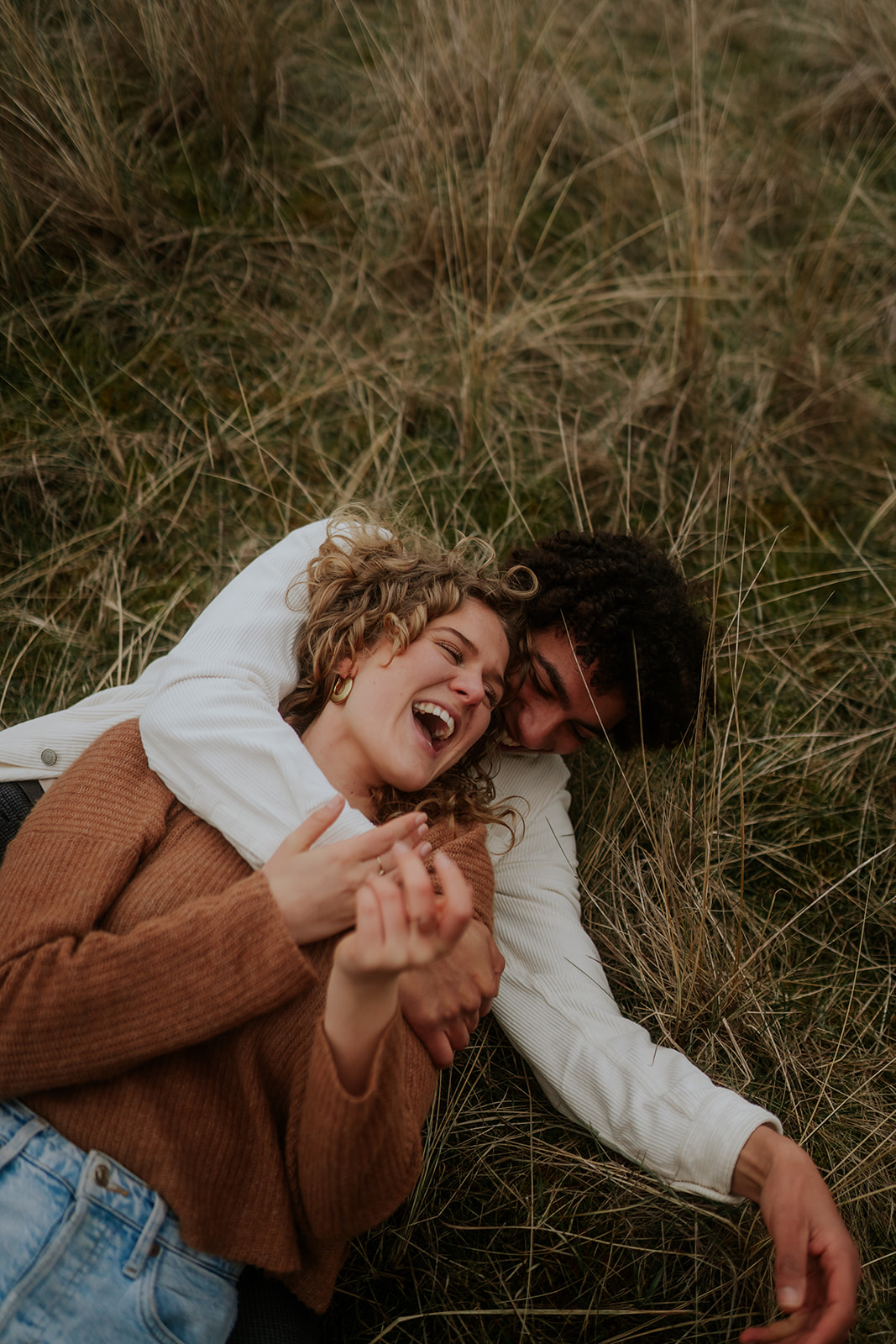 Couple laying on the ground and laughing brightly 