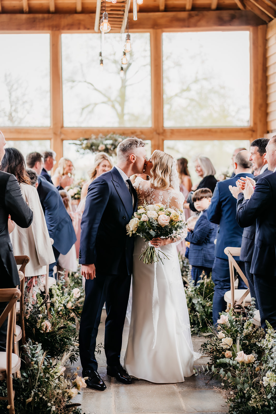 bride and groom kiss during wedding ceremony at  Barns & Yard