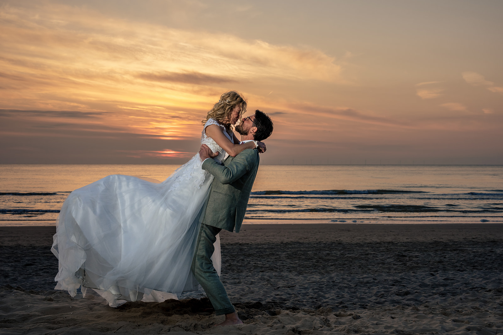 Sunset with a wedding couple on the beach with beautiful coloured sky at Club Zand in Castricum aan zee