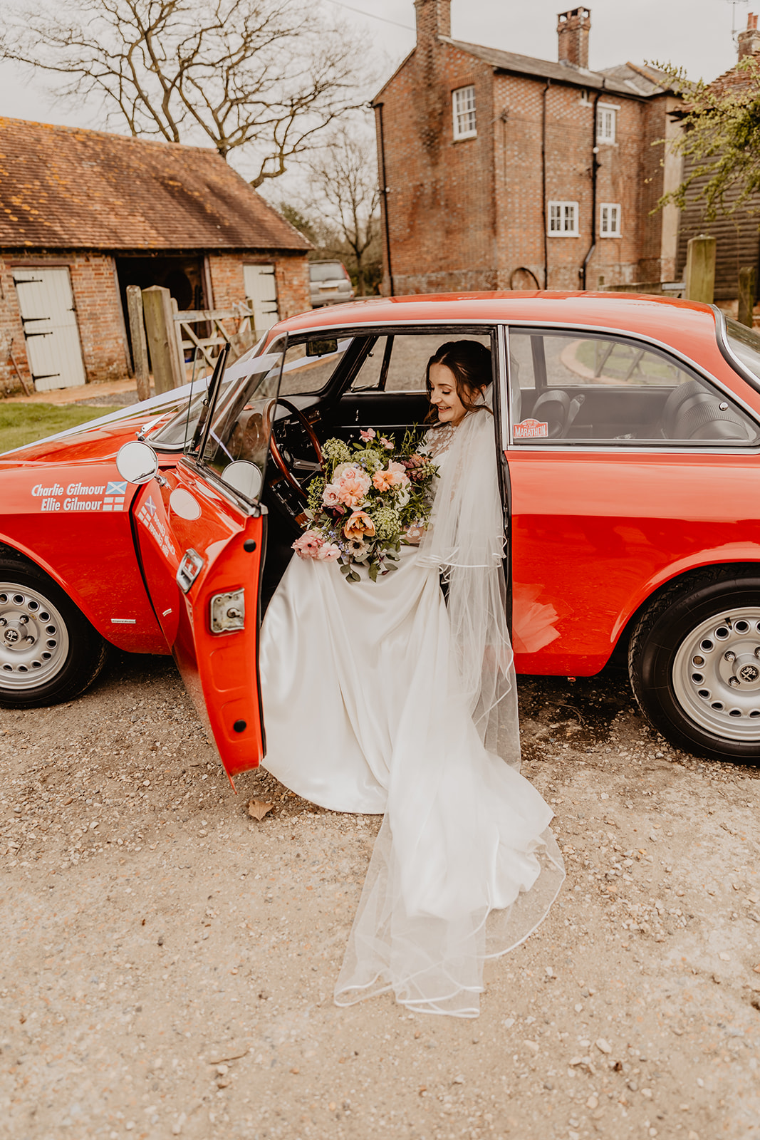 Bride getting out of the wedding car at a Secret Barn Wedding, West Sussex. By Olive Joy Photography