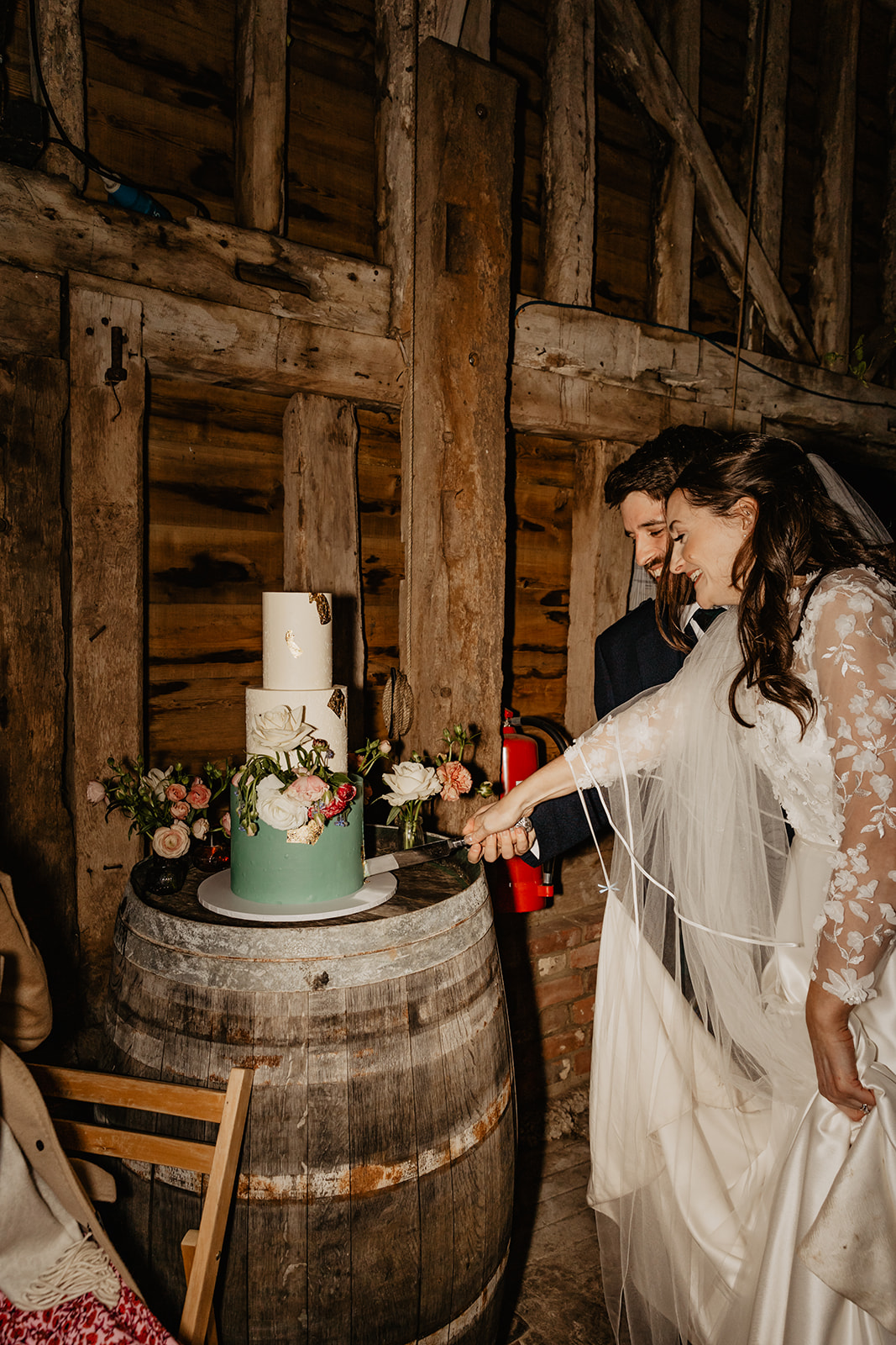 Bride and groom cutting the cake at a Secret Barn Wedding, West Sussex. By Olive Joy Photography