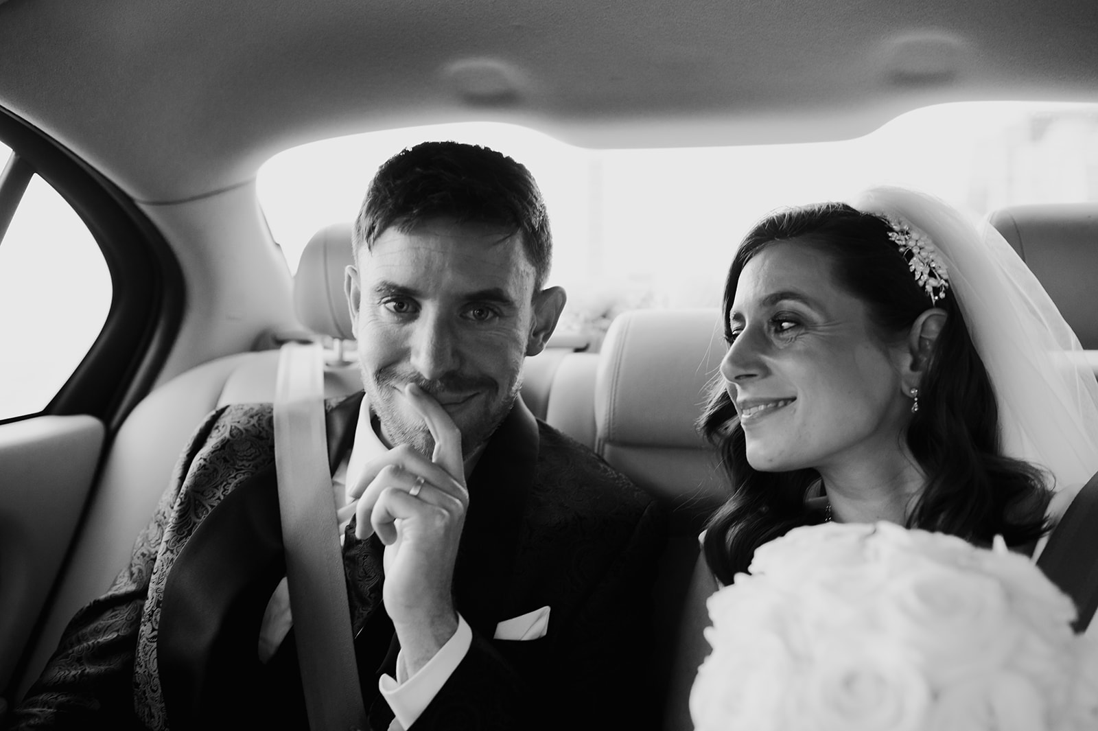 black and white of bride and groom sat in back of car at brighton winter wedding