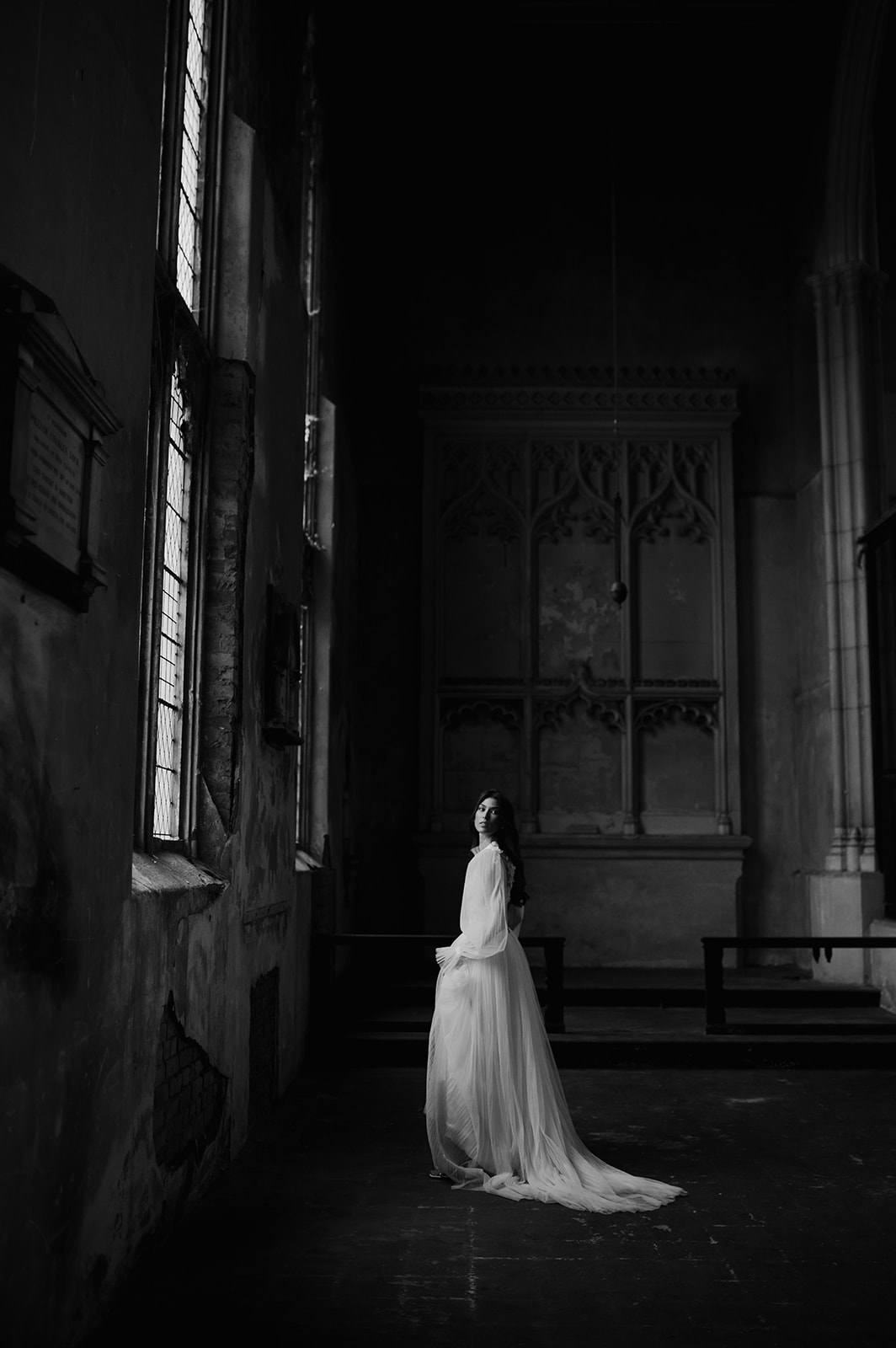 black and white bride standing in window light at London wedding 