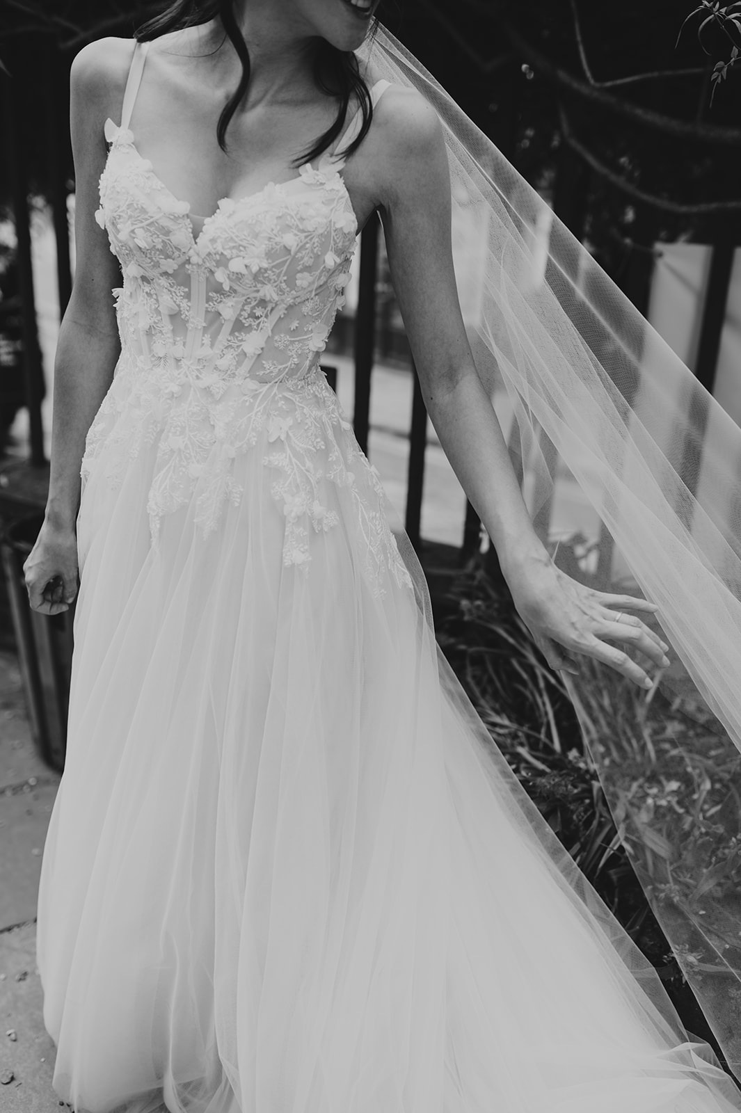 black and white of bride touching veil close up of floral appliqué wedding dress