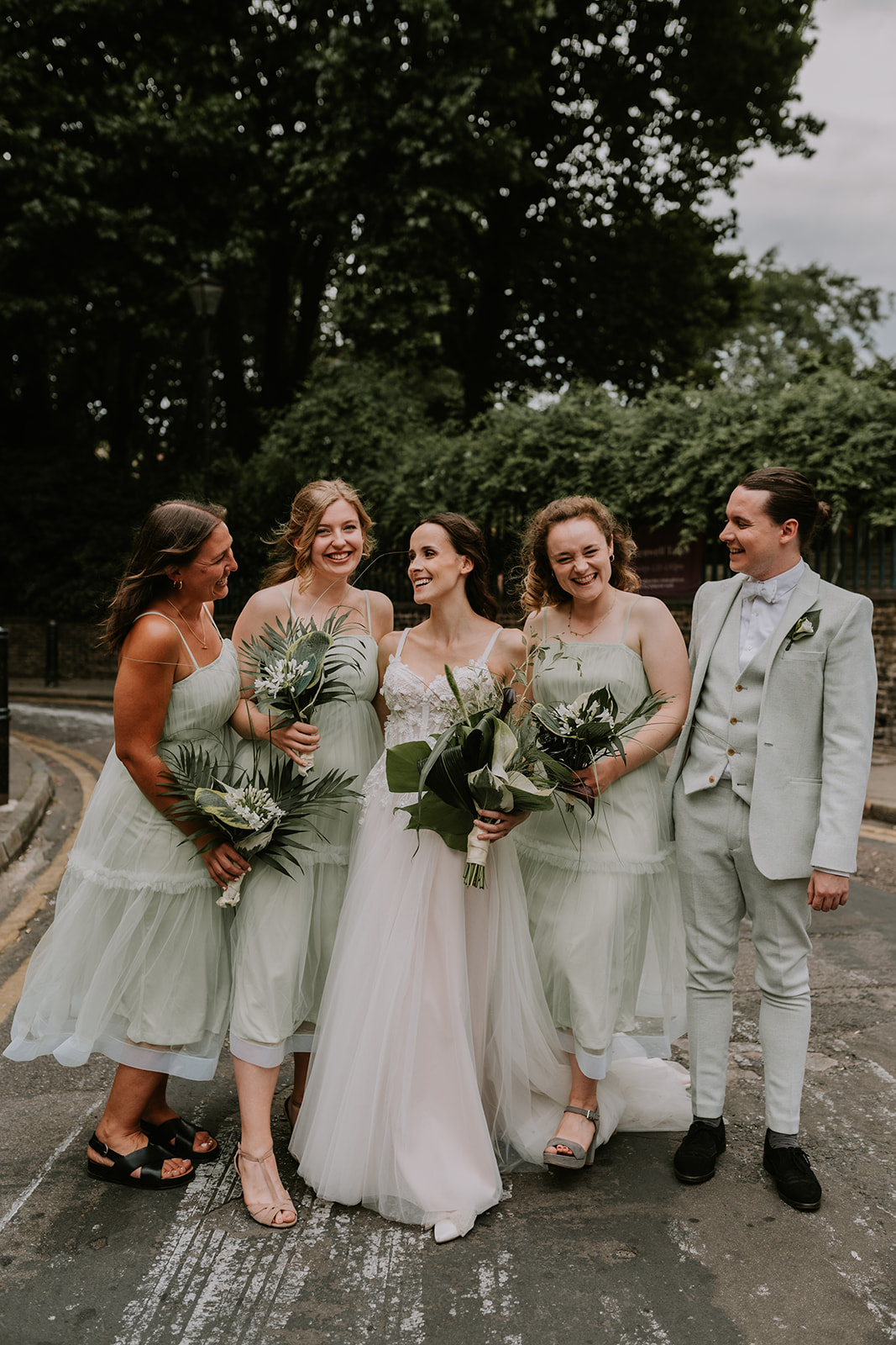 bride and bridesmaids hugging and smiling at one another at crypt on green London wedding