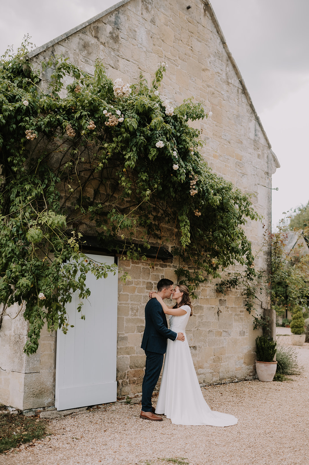 bride and groom kissing next to wall covered in green vines at Ashley wood farm wedding in Wiltshire 