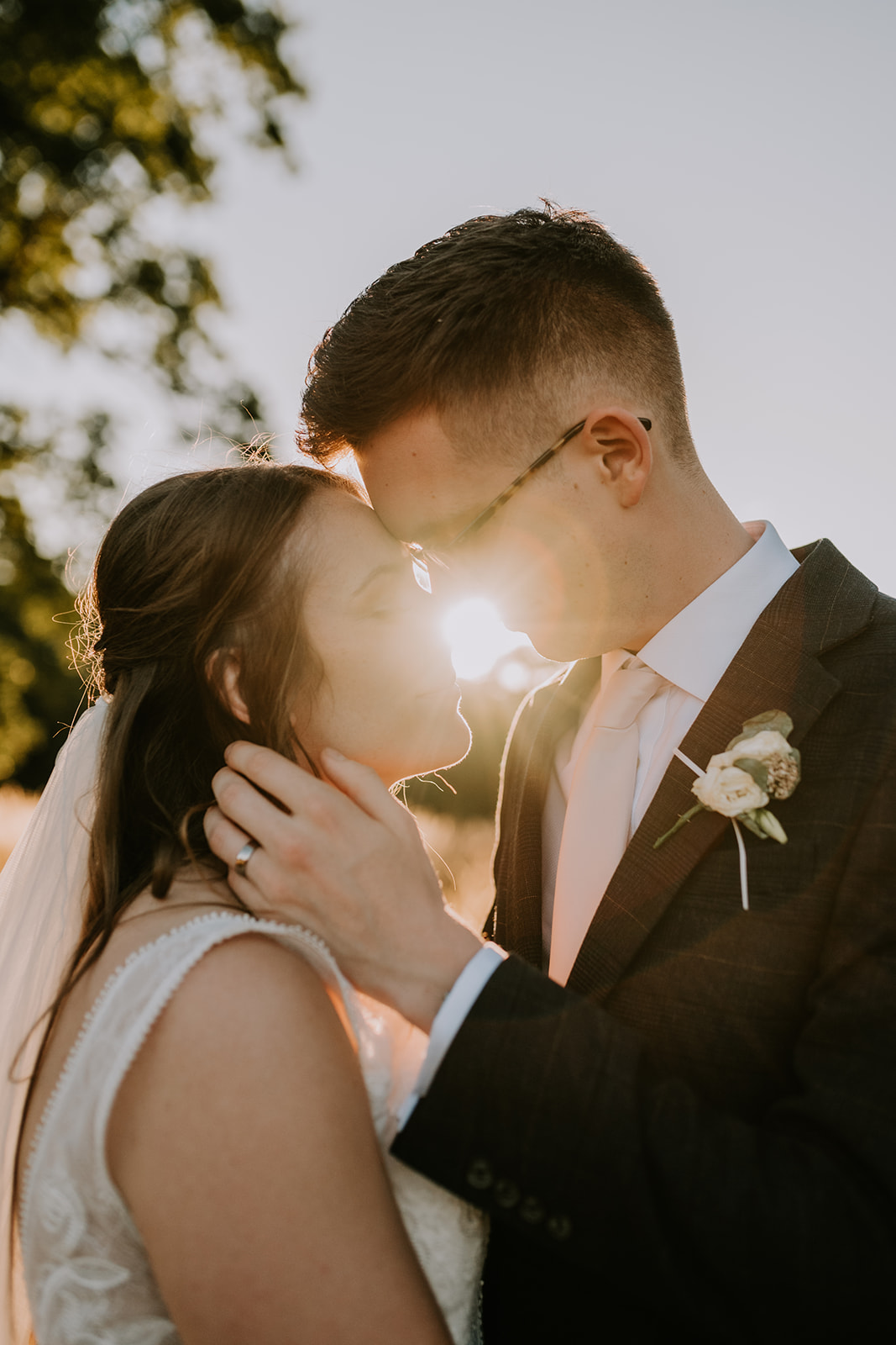 bride and groom touching foreheads with sunlight between them at golden hour at Surrey wedding 