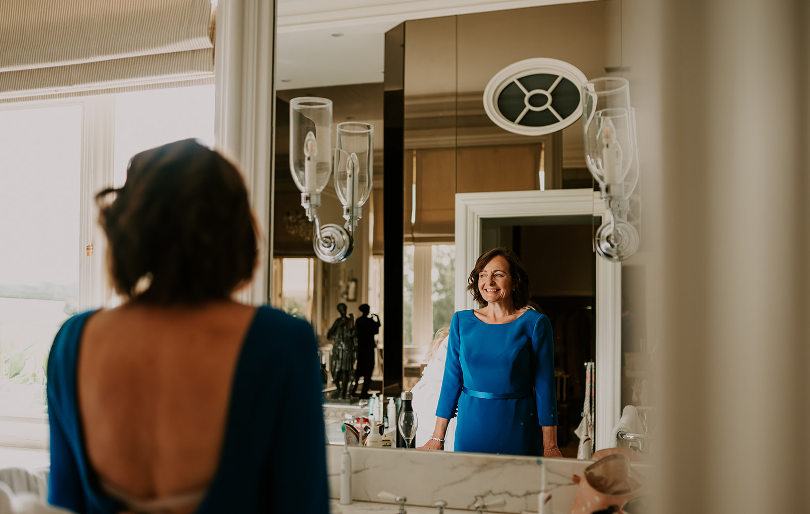 mother of bride smiling at reflection at summer cowdray house wedding 