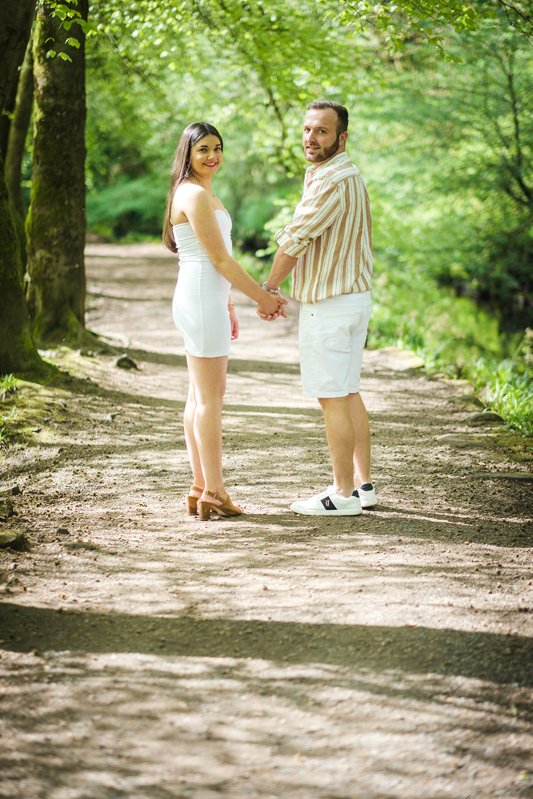 Engaged couple holding hands a looking back at Glasgow wedding photographer Steven Mitchell