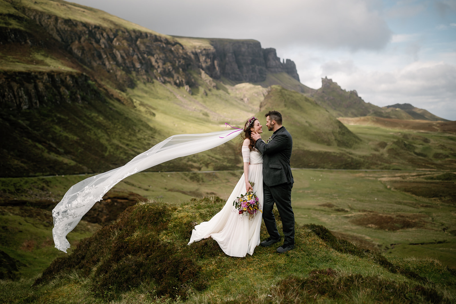 Becca, adorned in a stunning gown, gazes at Nick with love and anticipation against the backdrop of the Isle of Skye's e