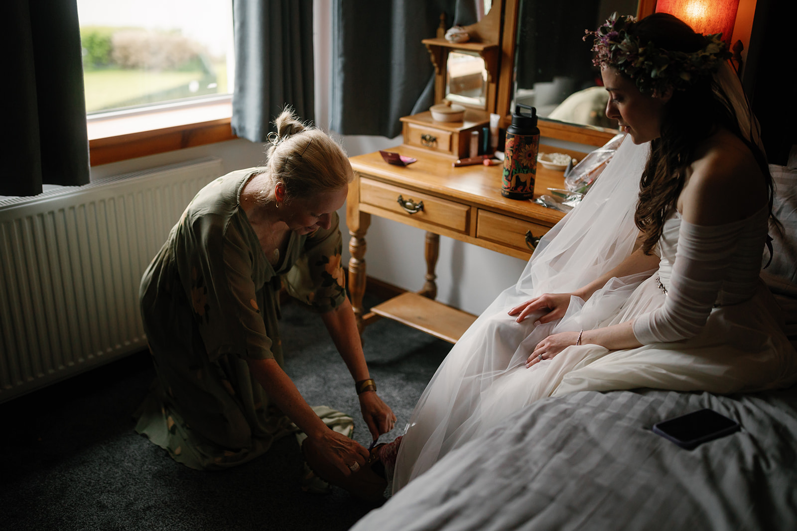 Becca's mother helps her with her boots, a cherished moment before her Isle of Skye elopement ceremony 