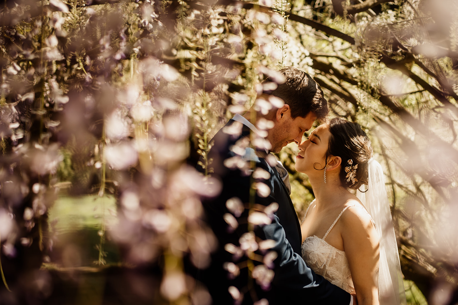Bride and groom embracing in the stunning gardens at Hampton Court Castle on their wedding day