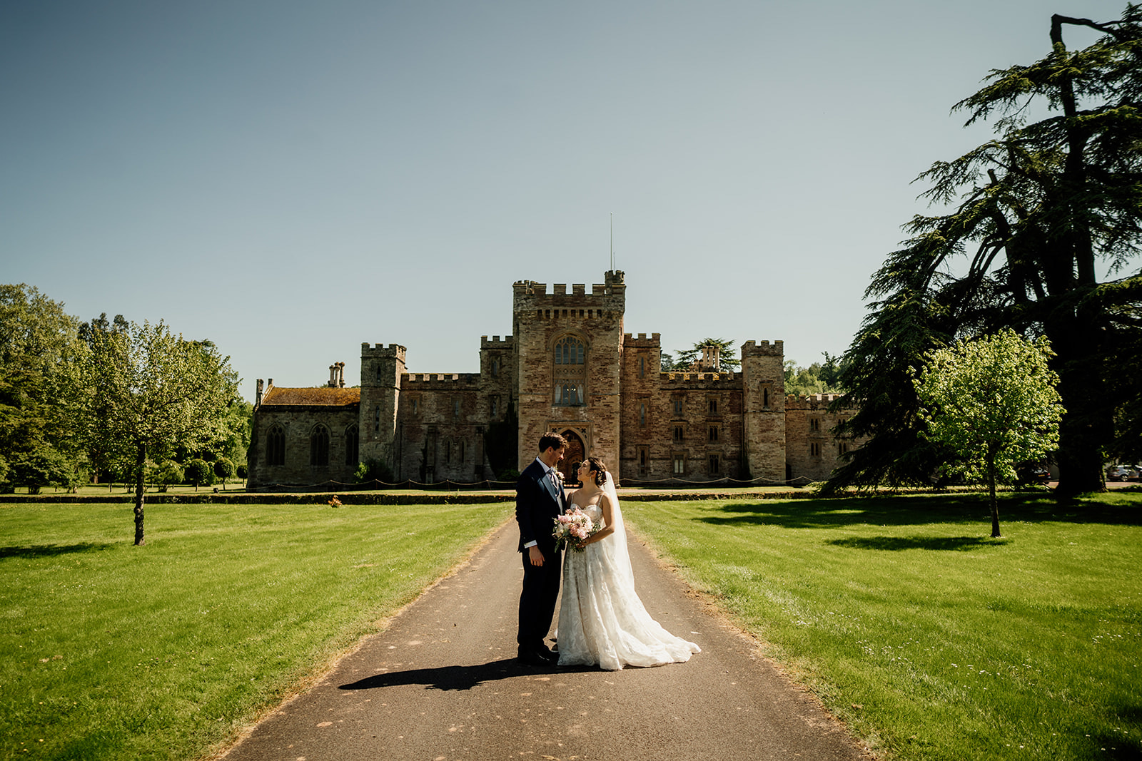 Bride and groom standing in front of Hampton Court Castle on their wedding day