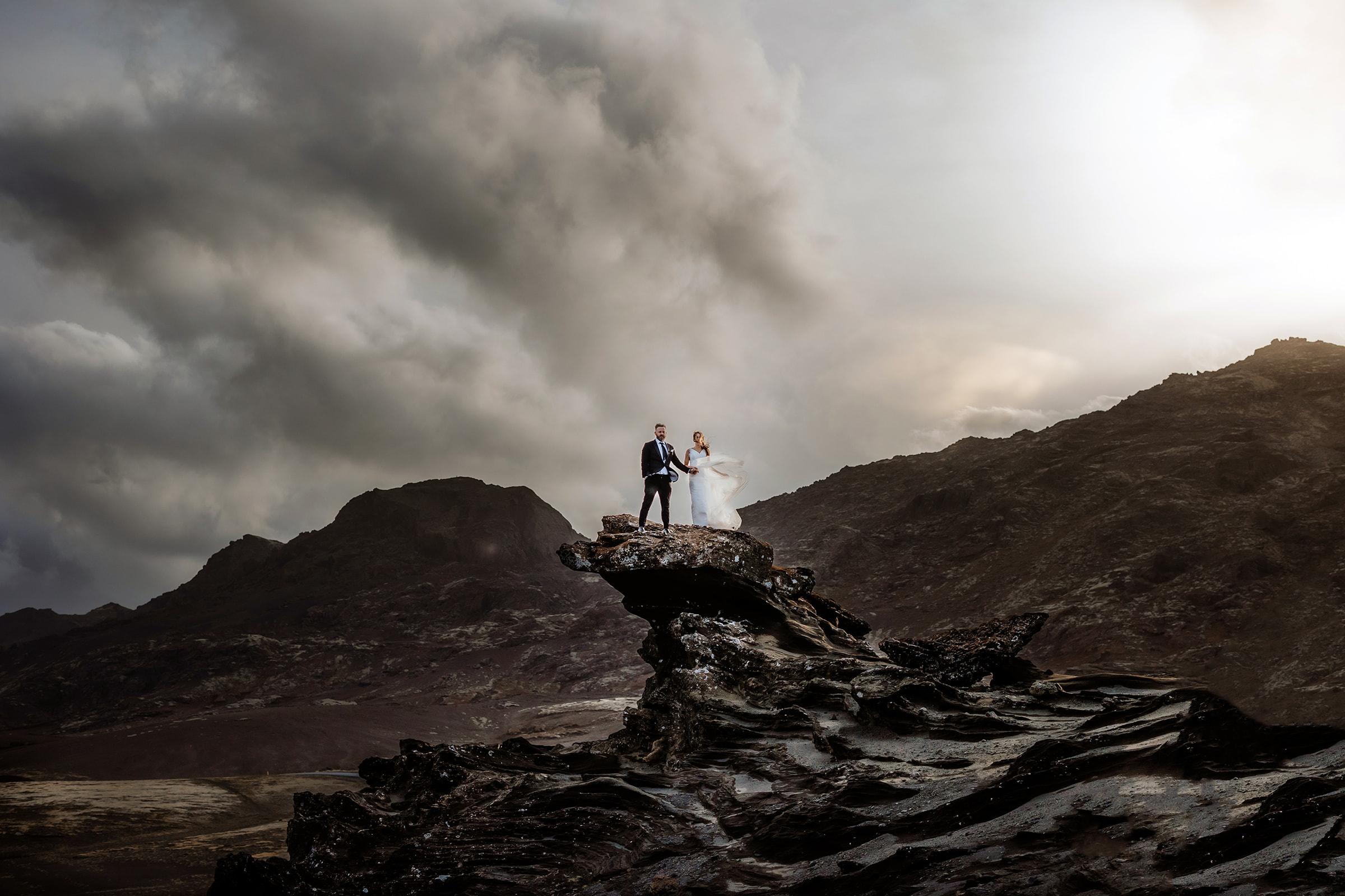 Married couple who eloped in Iceland standing on the top of a cliff