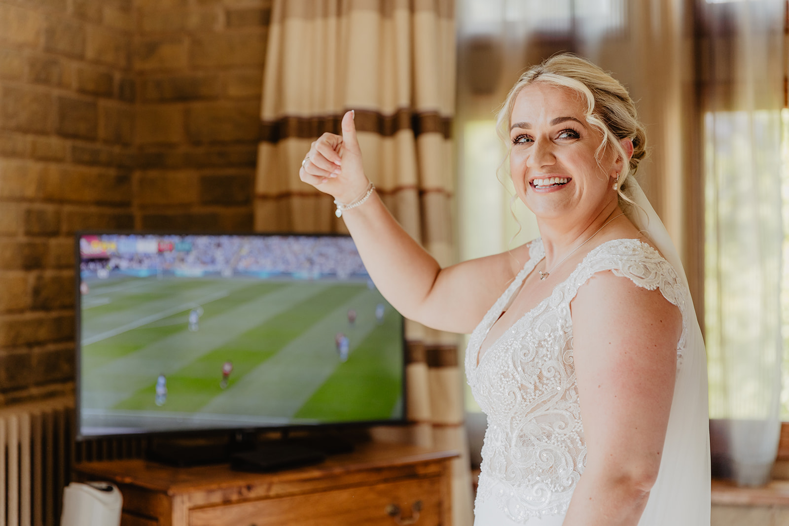 Bride watching football at a South Lodge, Sussex Wedding. By Olive Joy Photography