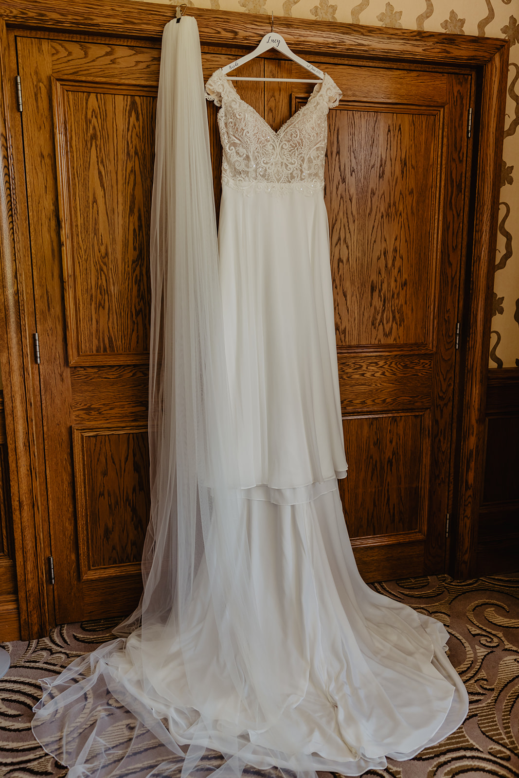 Bride's dress hanging up at a South Lodge, Sussex Wedding. By Olive Joy Photography