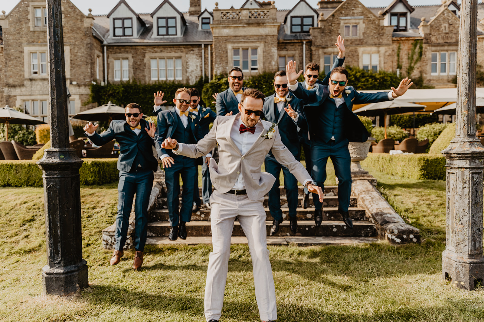 Groom jumps in front of bridal party at a South Lodge, Sussex Wedding. By Olive Joy Photography