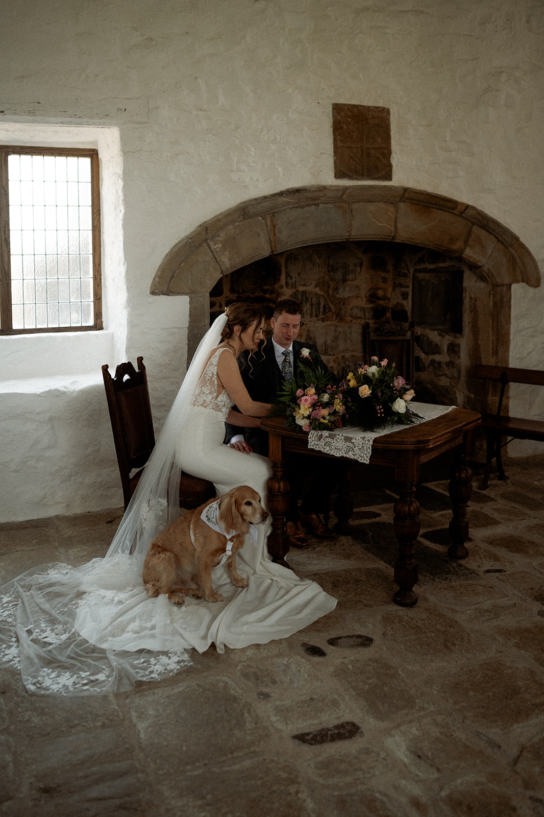 a couple who eloped to Wales signing the register with a dog sitting on the bride's dress at Penarth Fawr