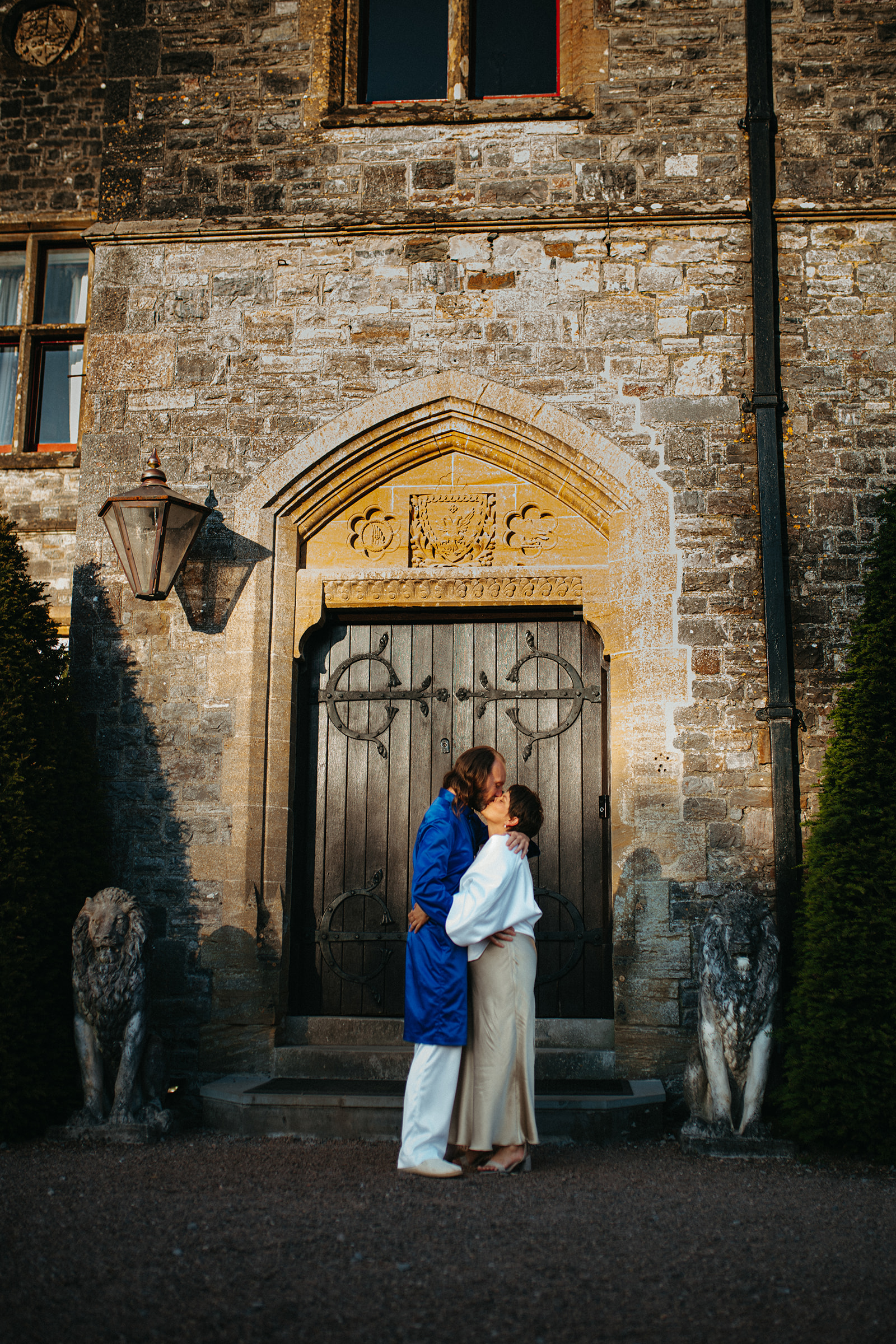 Romantic kiss of a couple in front of the majestic Huntsham Court castle, England.