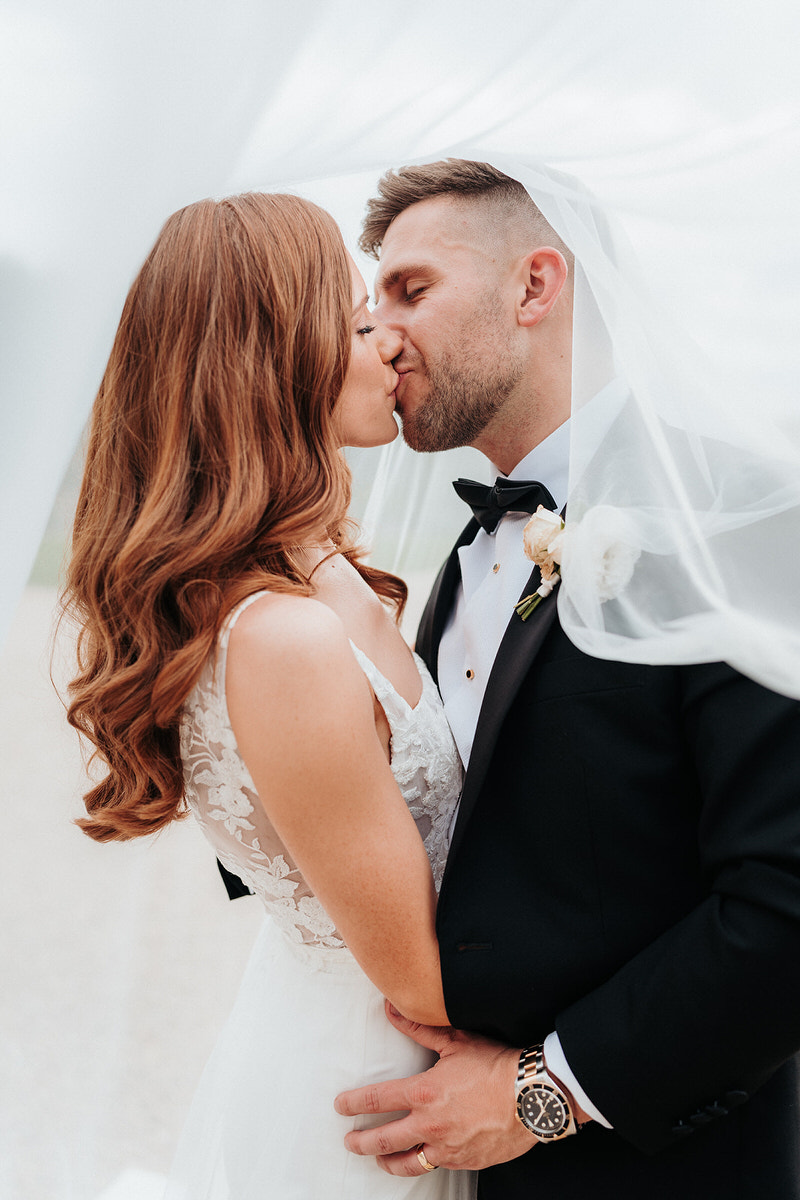 Bride and groom kissing under the brides veil
