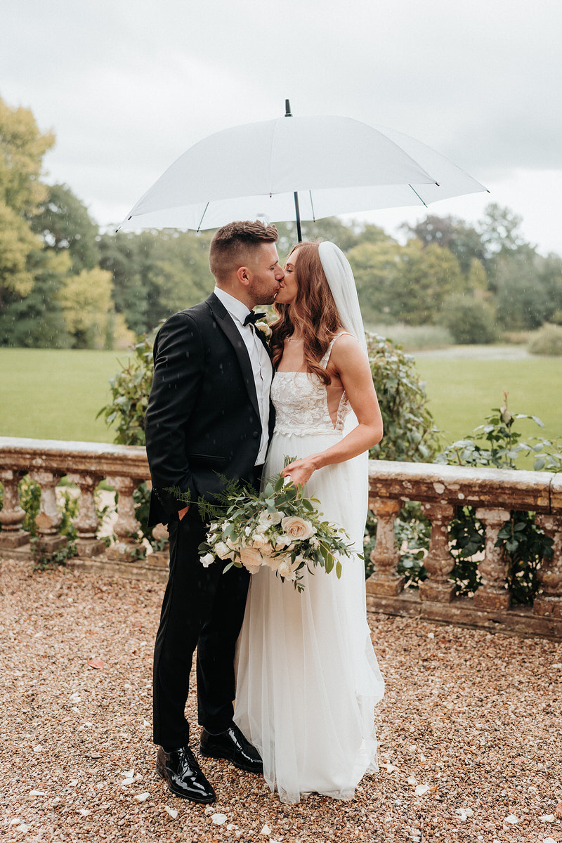 Bride and groom posing for the wedding photographer and videographer in the rain at Brympton House 