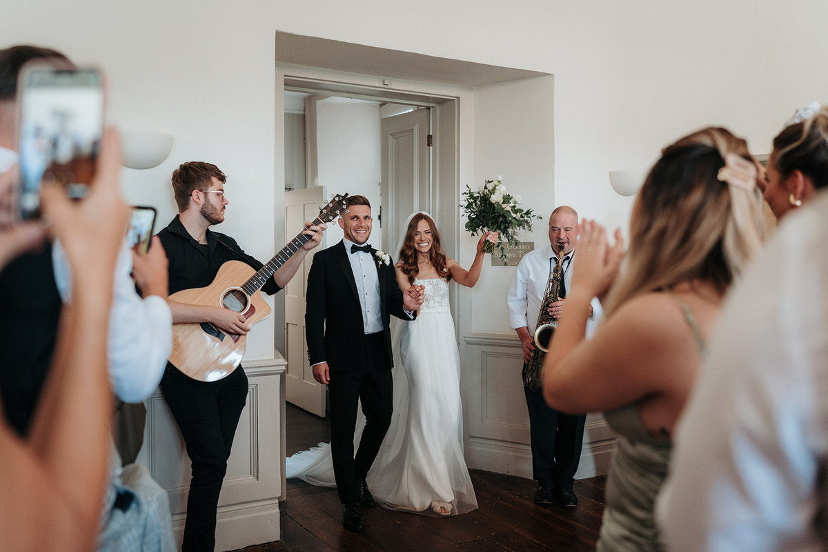 bride and groom welcomed into the ballroom with guests cheering 