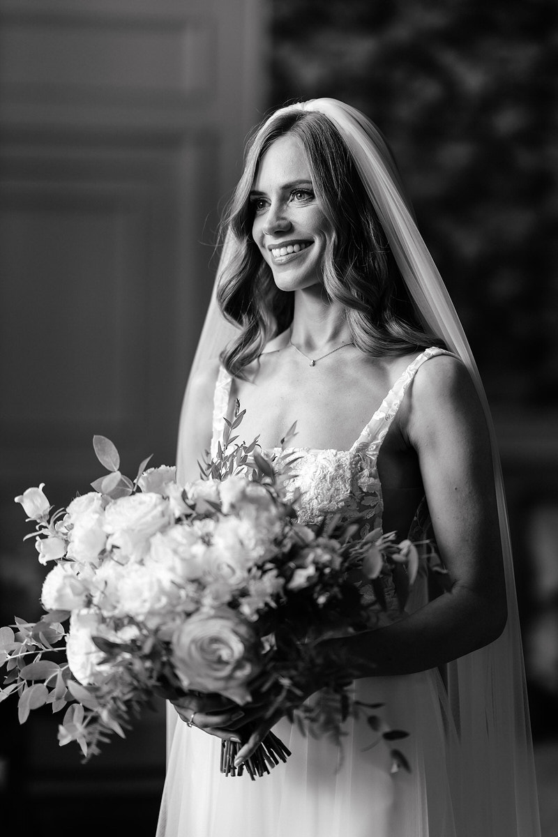 Bride looking down at flowers in black and white