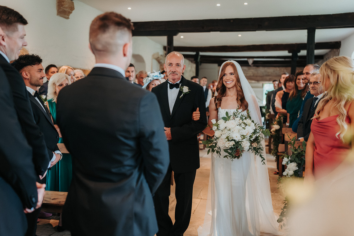 bride walks down the aisle at Brympton House with her Father