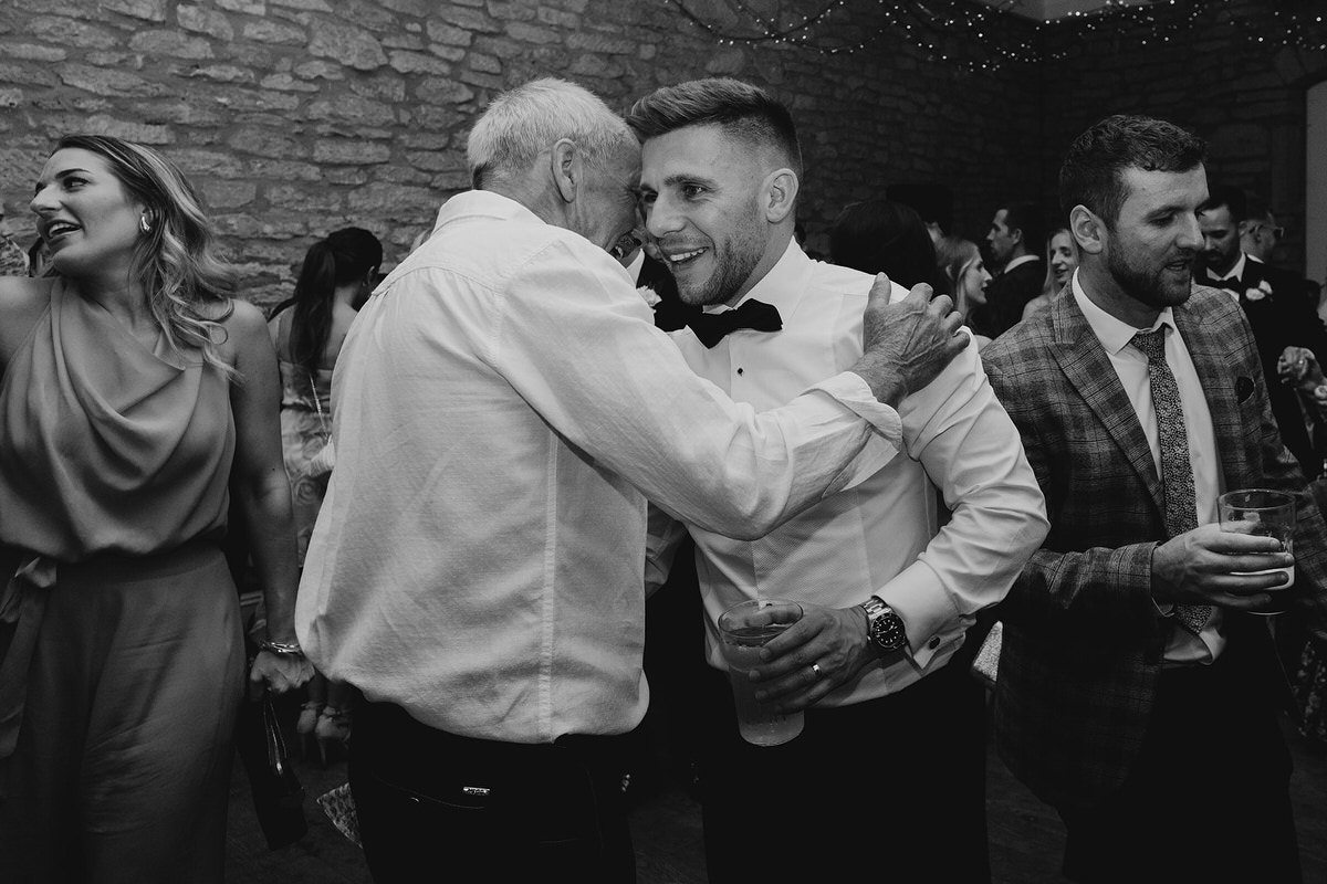 groom embraces father of the bride on the dancefloor
