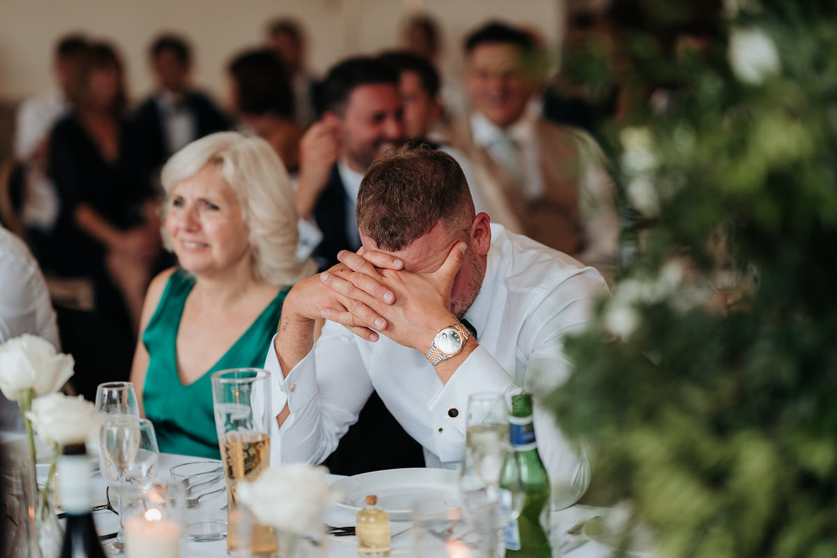 guest with hands over his face during the wedding speeches