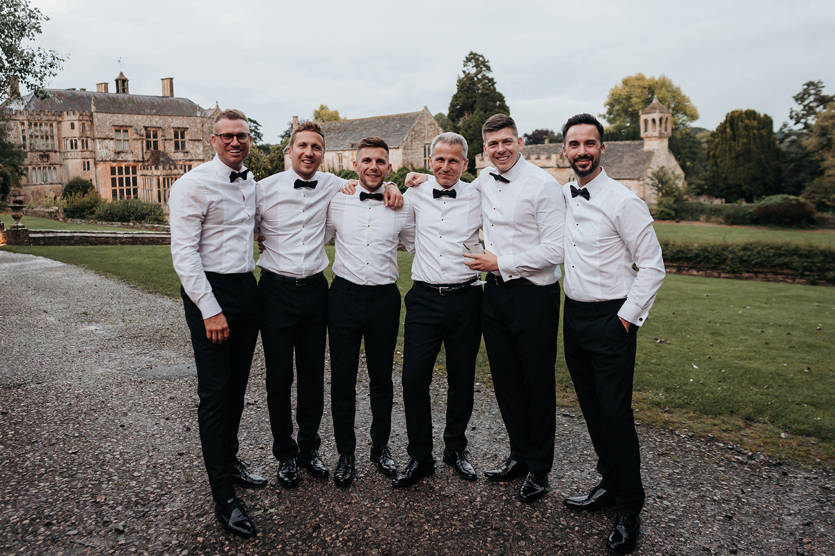 the groom party posing for wedding photographer outside the party barn at Brympton House