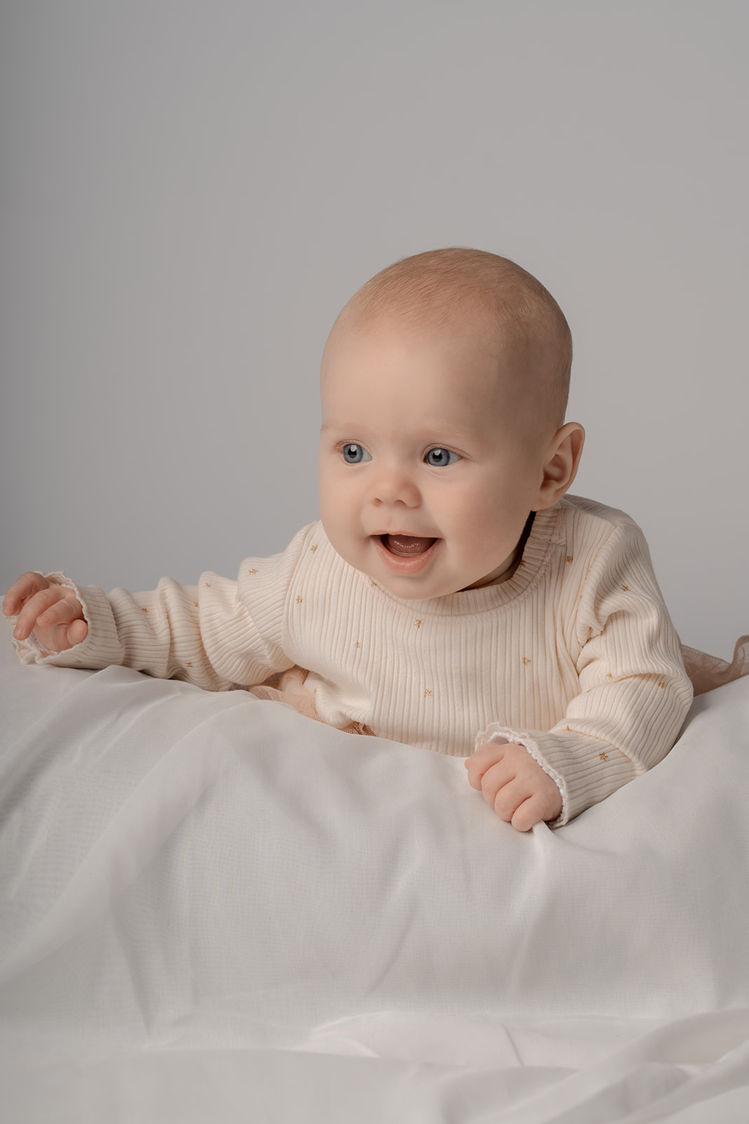 Billede af baby på 5 måneder i naturligt setop, hvor hun ligger på maven og smiler
