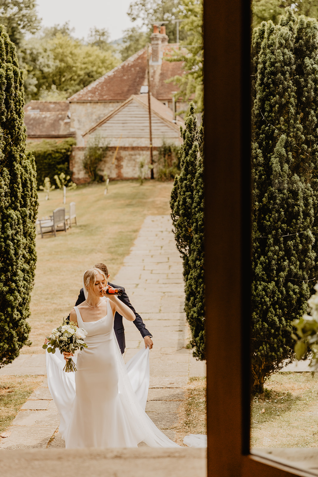 Bride and groom amongst tress and greenery at a Bury Manor Barn Wedding in Sussex. Photographer OliveJoy Photography.