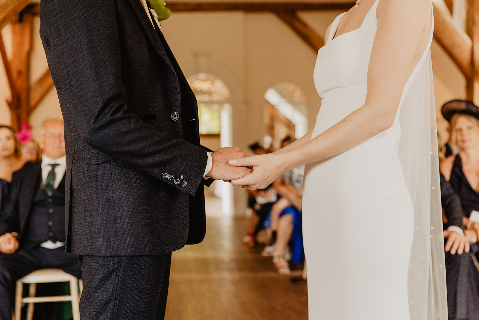 Bride and Groom holding hands during vow at a Bury Manor Barn Wedding in Sussex. Photographer OliveJoy Photography.