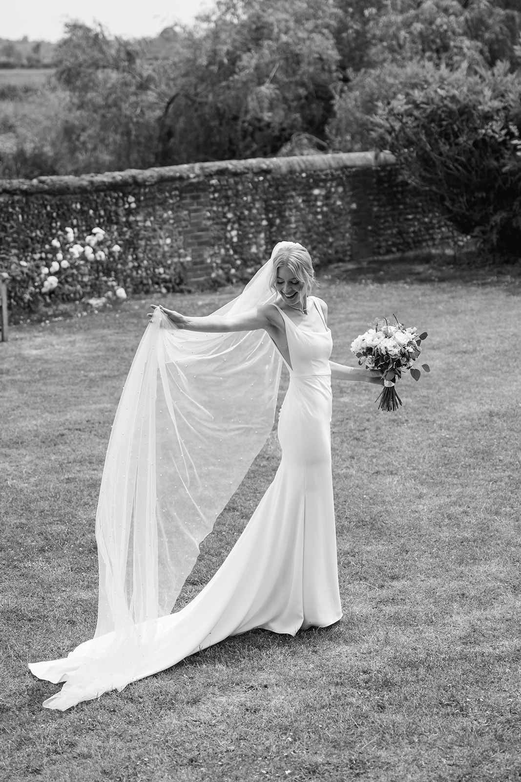 Bride waving dressat a Bury Manor Barn Wedding in Sussex. Photographer OliveJoy Photography.
